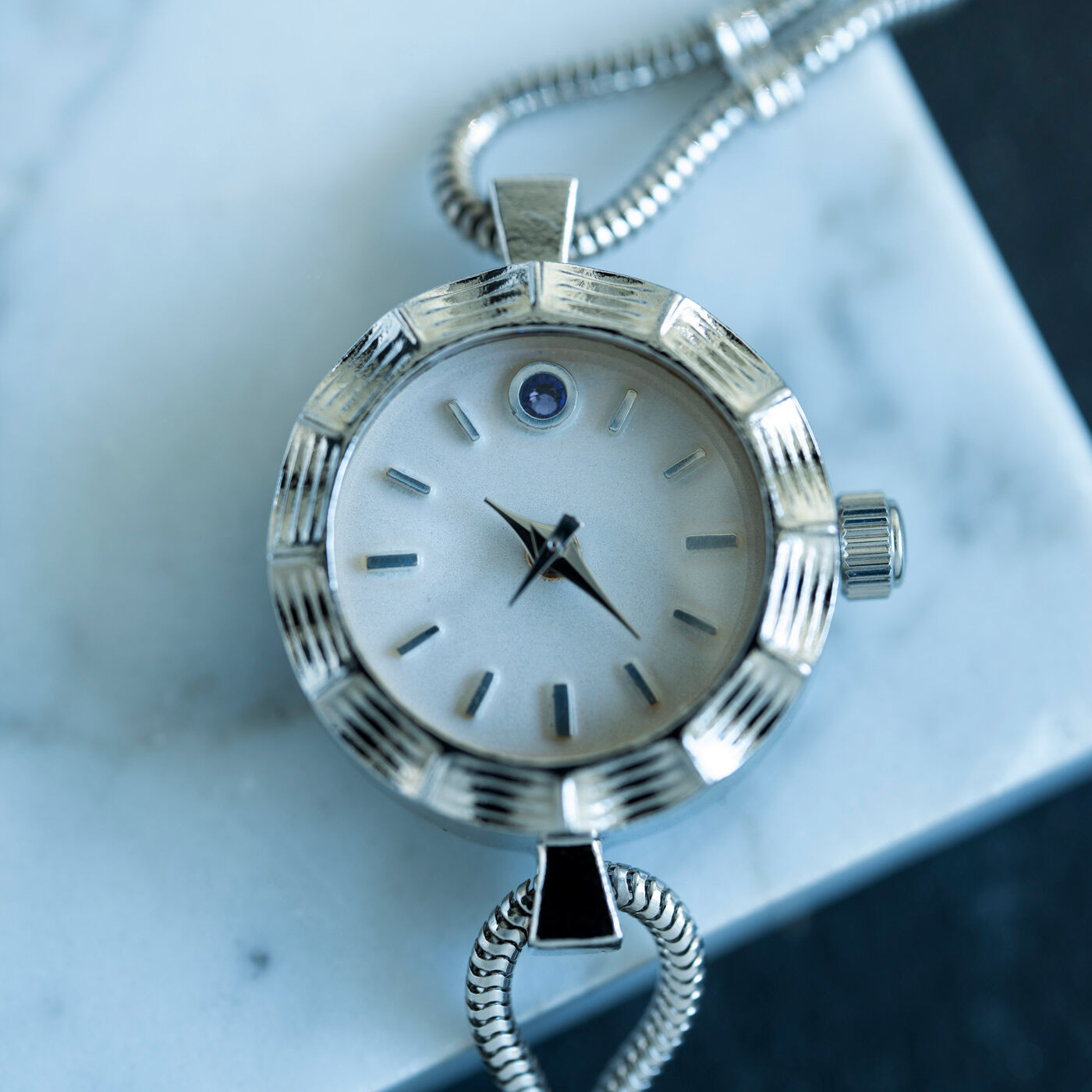 ＆Stories|滋賀の時計職人とヴィンテージショップオーナーが作った　ドレスウォッチ〈シルバー色〉|フレームにも装飾を施し、上品なパールホワイトの文字盤には深みのあるタンザナイト色（青紫色）のラインストーンを一粒。